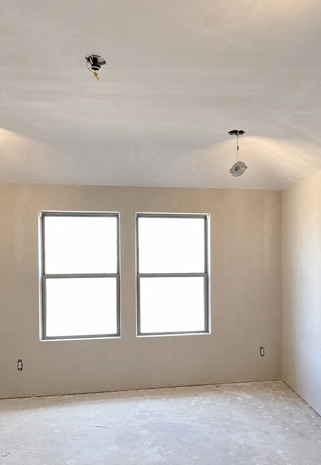 Room with two windows, walls, and ceiling during drywall finishing
